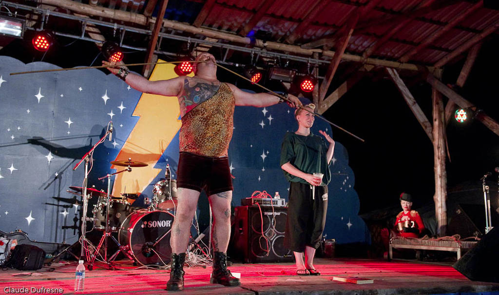 Strongman The Mighty Leviticus, of The Blue Mushroom Sirkus Psyshow performs at an earlier edition of ShazamFest. I do believe that he is bending steel rebar with his teeth. (Does his dentist know about this?  Photo, by Claude Dufresne, from ShazamFest web site.
